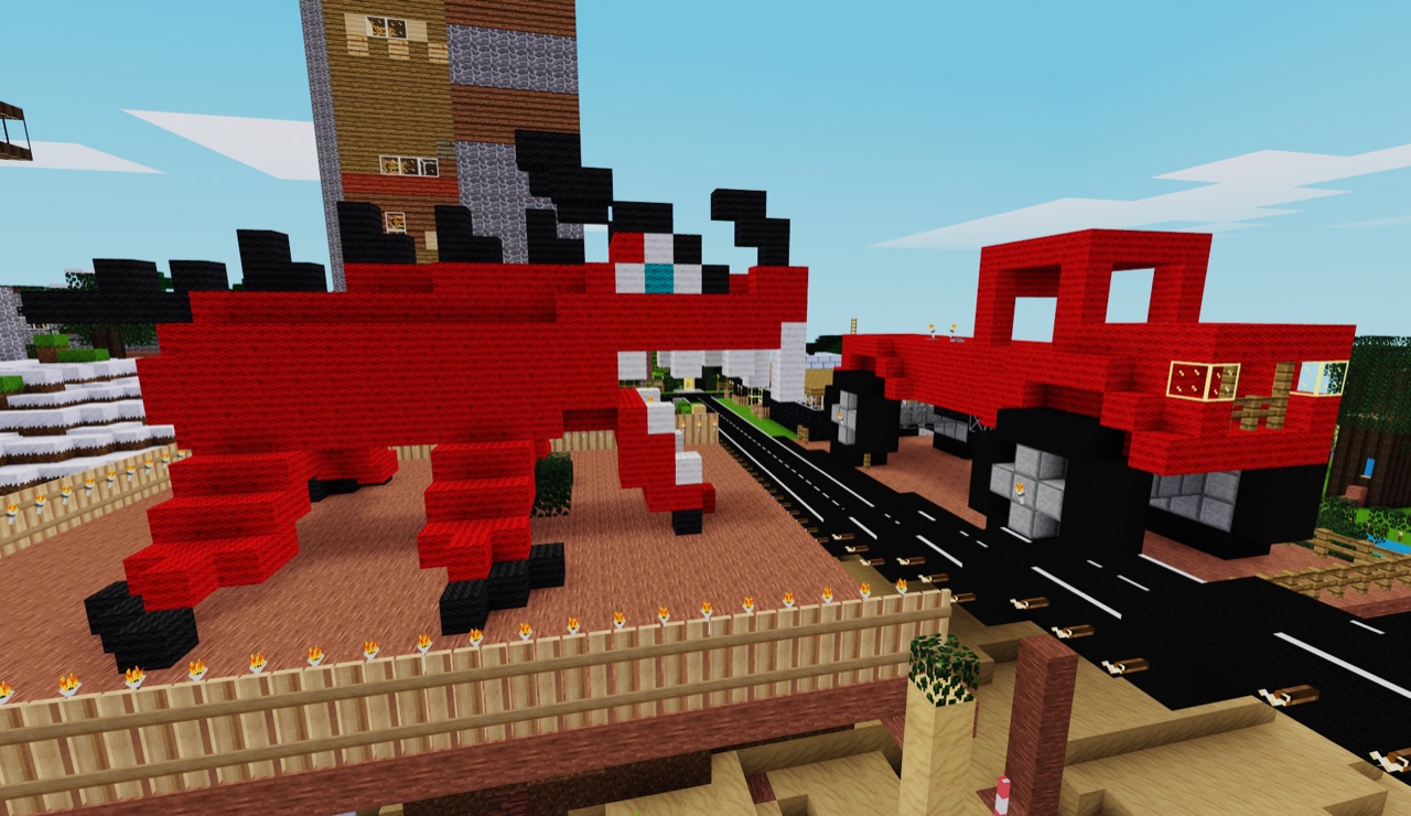 Red dinosaur and a red truck along a rail line